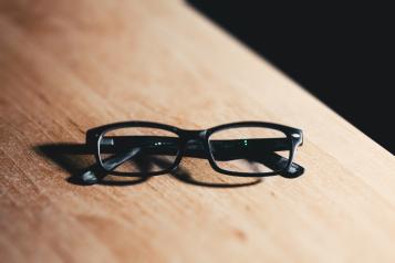 Pair of black spectacles on a wooden surface