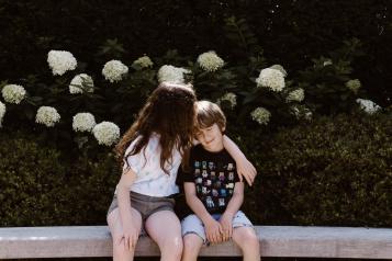 Young boy and girl outside hugging