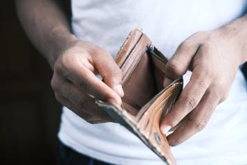 Man opening empty brown wallet