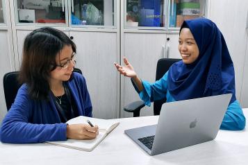 Two people sat at a computer talking