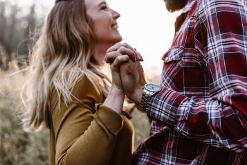 Woman smiling at man, facing each other and holding hands