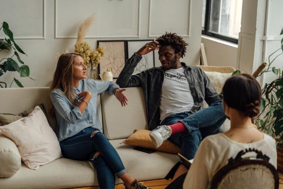 Group of two women and a man sitting on sofas talking