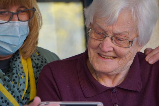 Elderly woman being helped with mobile device