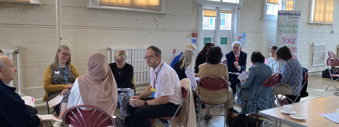 People meeting in a hall sitting in groups having discussions 