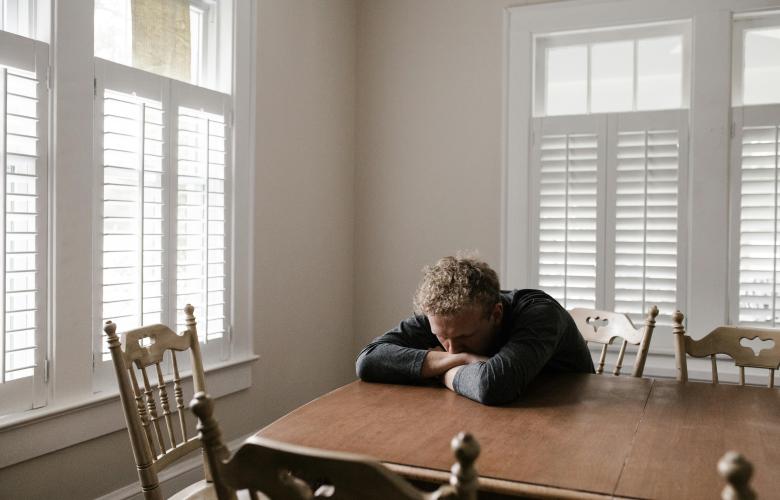 A man alone and isolated, sat at a table. 