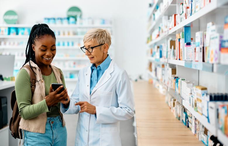 Female pharmacist talking to a young woman with pharmacy store in background