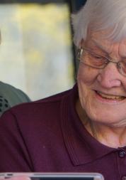 Elderly woman being helped with mobile device