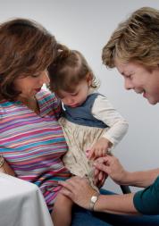 Nurse giving an infant a vaccination while parent holds the baby.