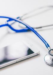 blue stethoscope and grey mobile phone on white background